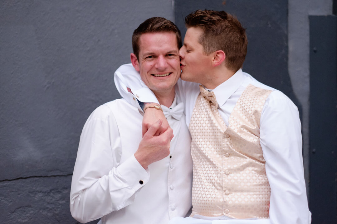 Two men kiss eachother at their wedding