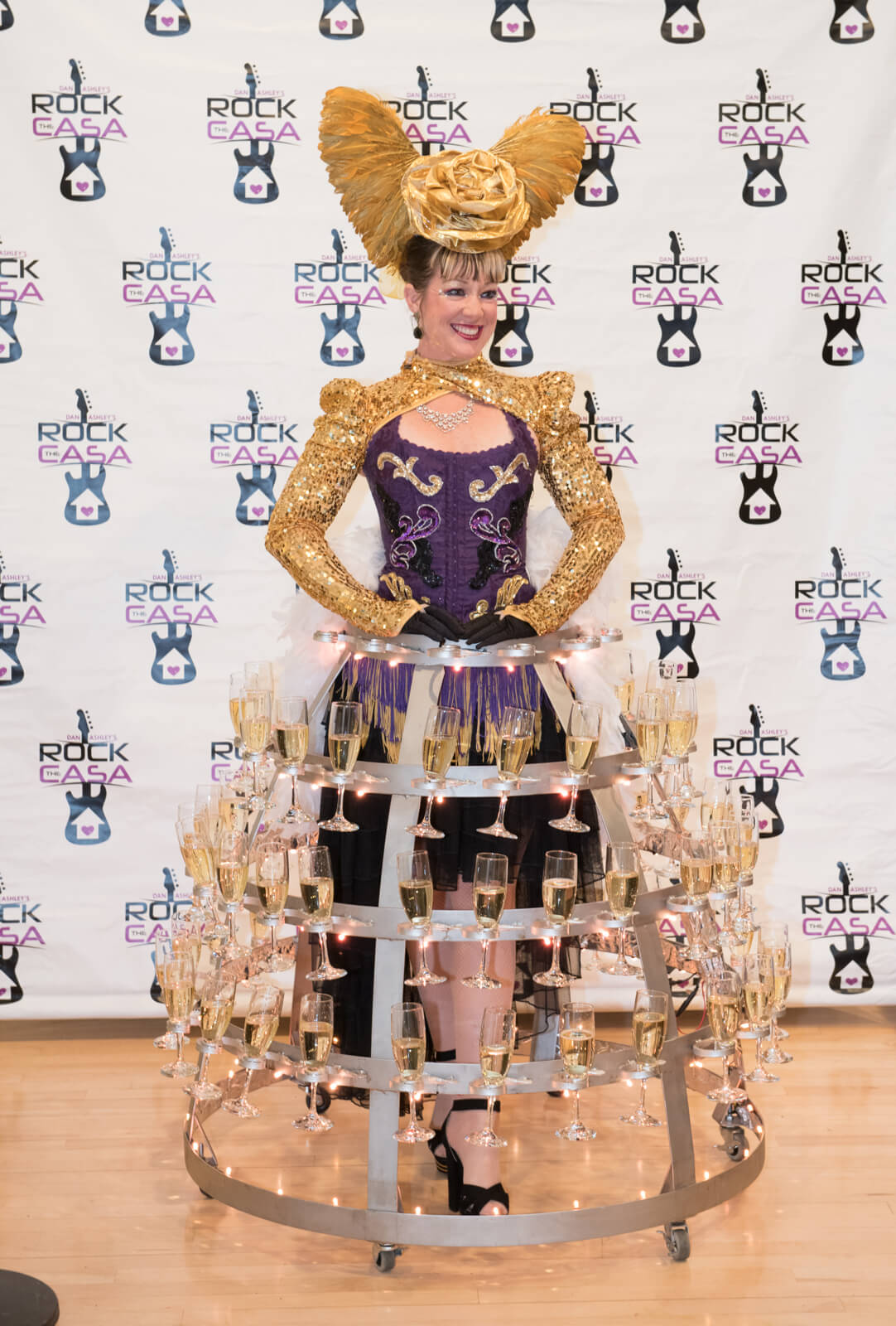 Woman at event dressed in dress made of champagne glasses.