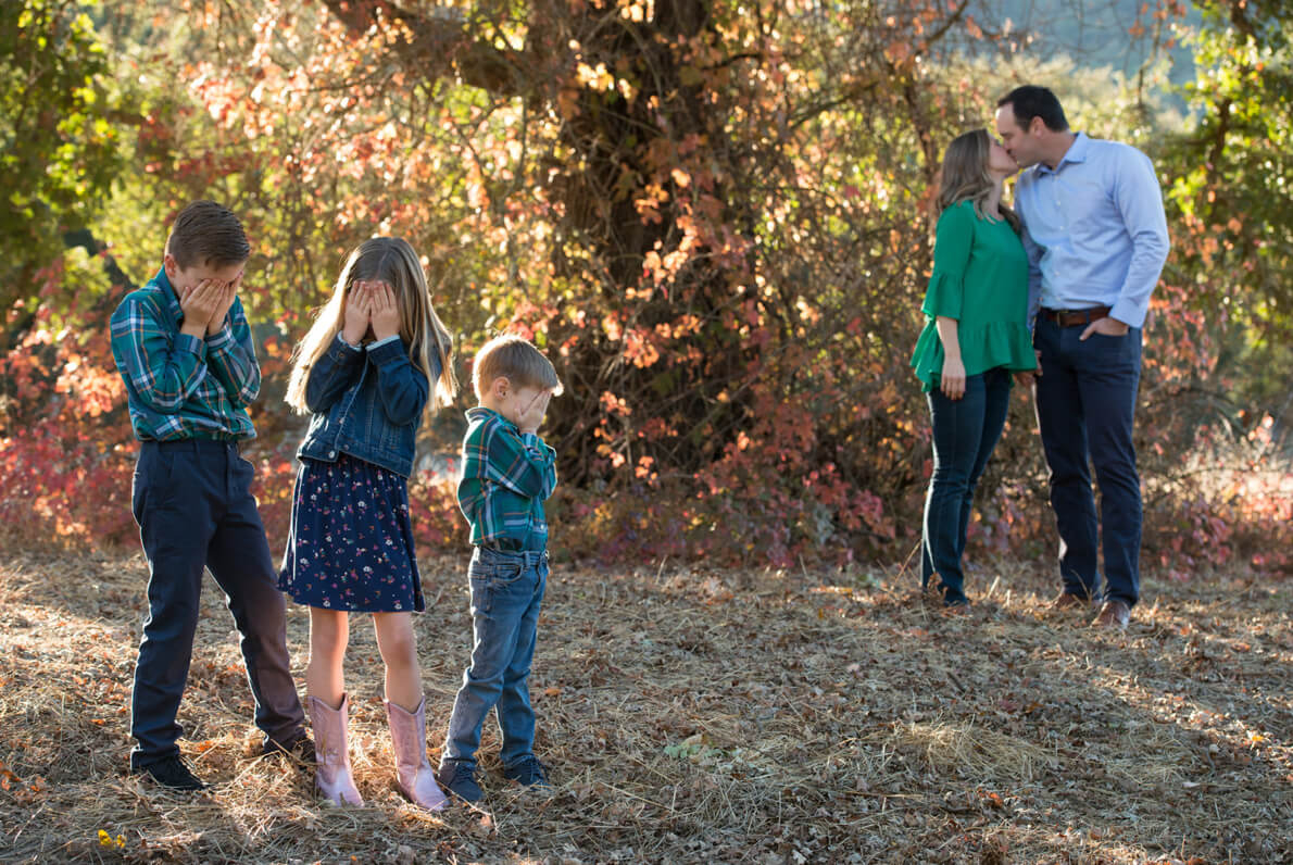 Kids cover their faces as their parents kiss